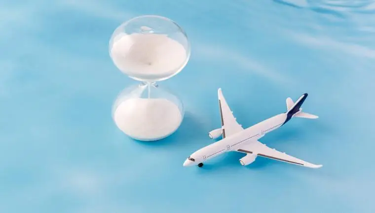 Letadlo Tui a přesýpací hodiny na pozadí oblohy