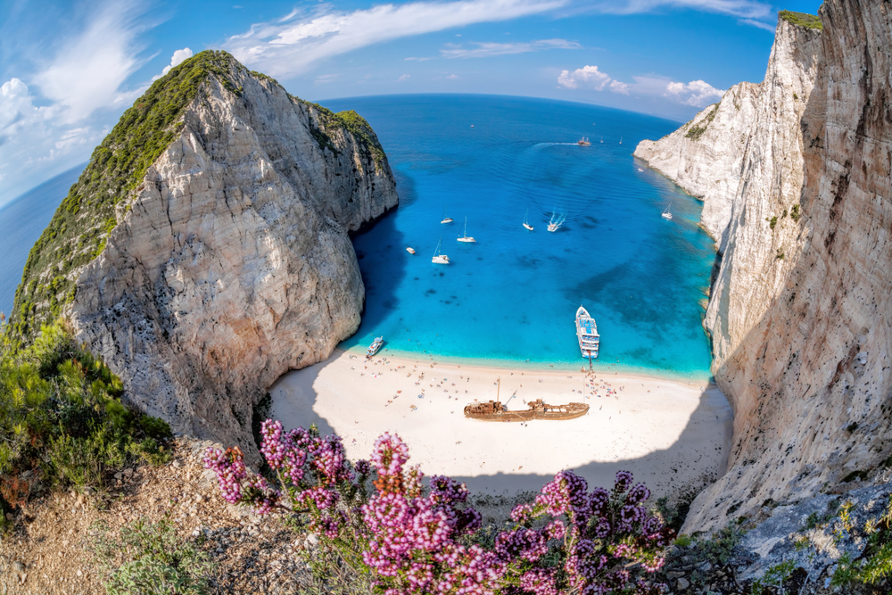 Jarní dovolená na řeckých ostrovech – na kterém bude nejtepleji? 10 Pláž Navagio s vrakem lodi a květinami na ostrově Zakynthos, Řecko