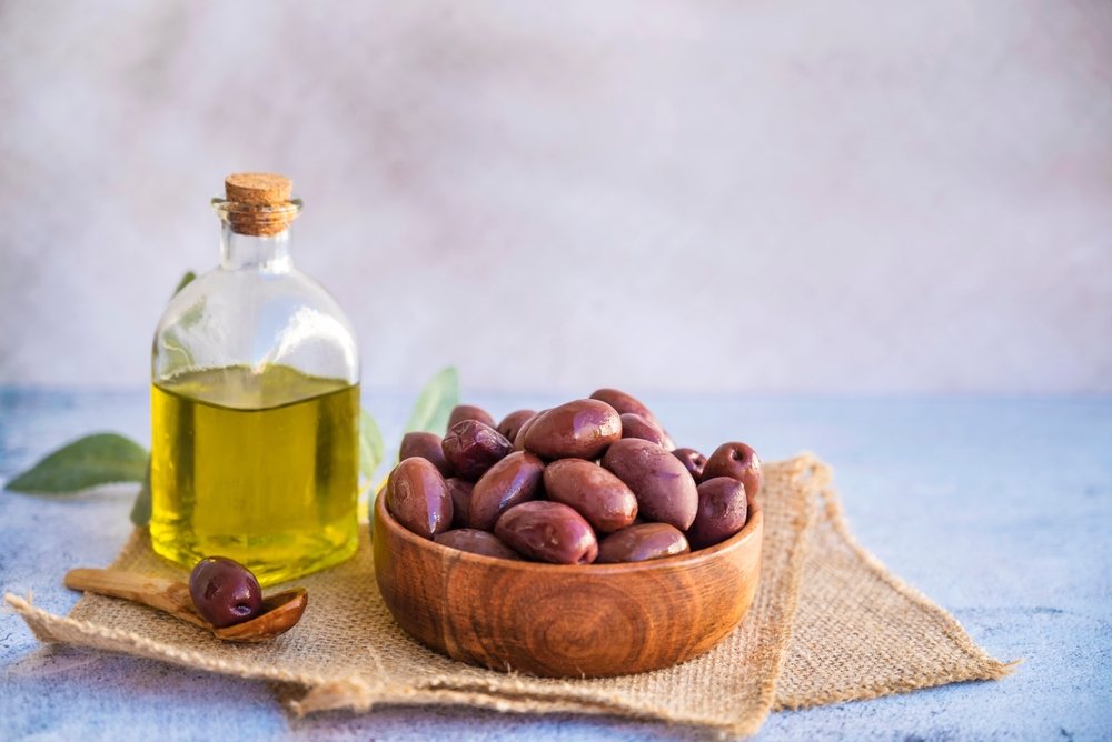 Řecký olivový olej a olivy kalamata v dřevěné misce