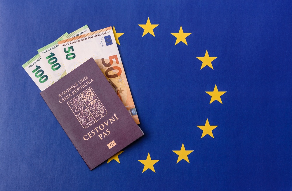 Český cestovní pas a euro bankovky na pozadí vlajky Evropské unie