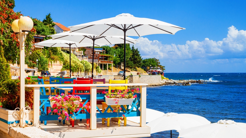 Kavárna na bulharském pobřeží s barevnými židlemi a čistým, modrým mořem