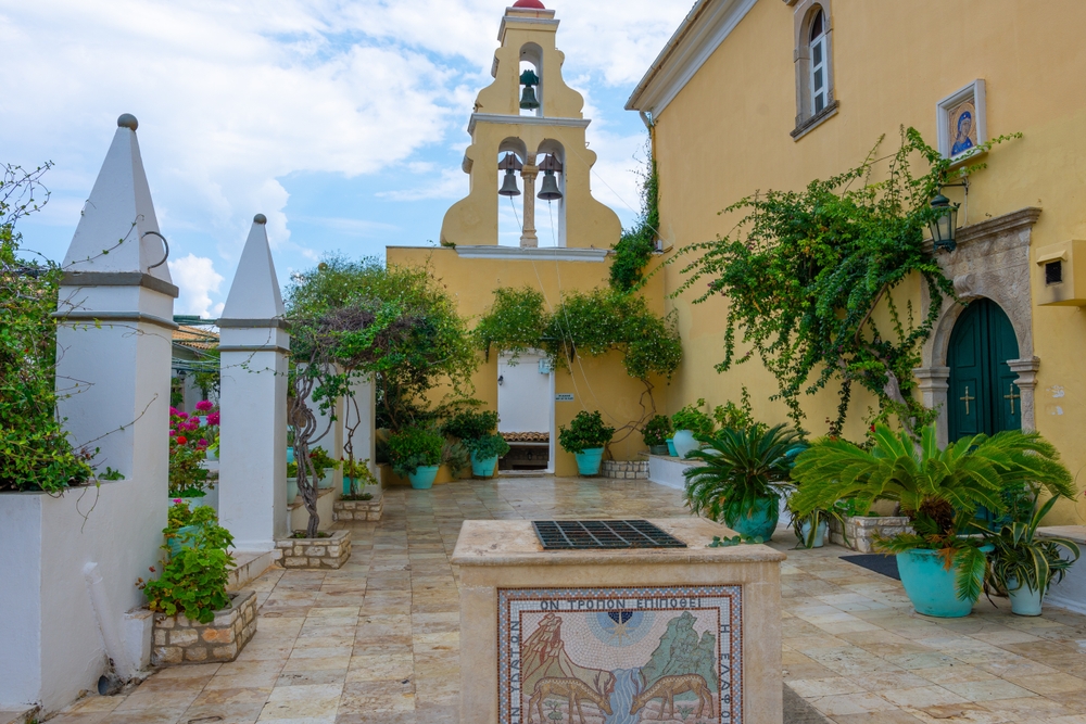 Nádvoří kláštera Klášter Panagia Theotokou s kamenným obloukem a květinami