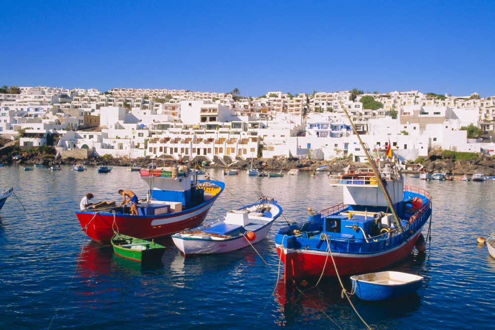 Dovolená na Lanzarote – co vidět během pobytu na ostrově? Atrakce a zajímavosti 4 Puerto del Carmen na Lanzarote s barevnými lodičkami a bílými budovami