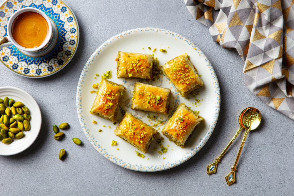 Tradiční albánská kuchyně – zažijte pravou chuť Balkánu! 6 Baklava na bílém talíři a šálek kávy na šedém pozadí
