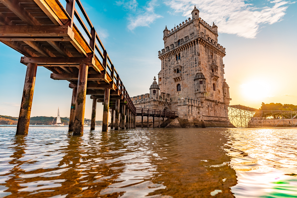 Pohled na malý most přes řeku a známou věž Torre de Belém v Lisabonu