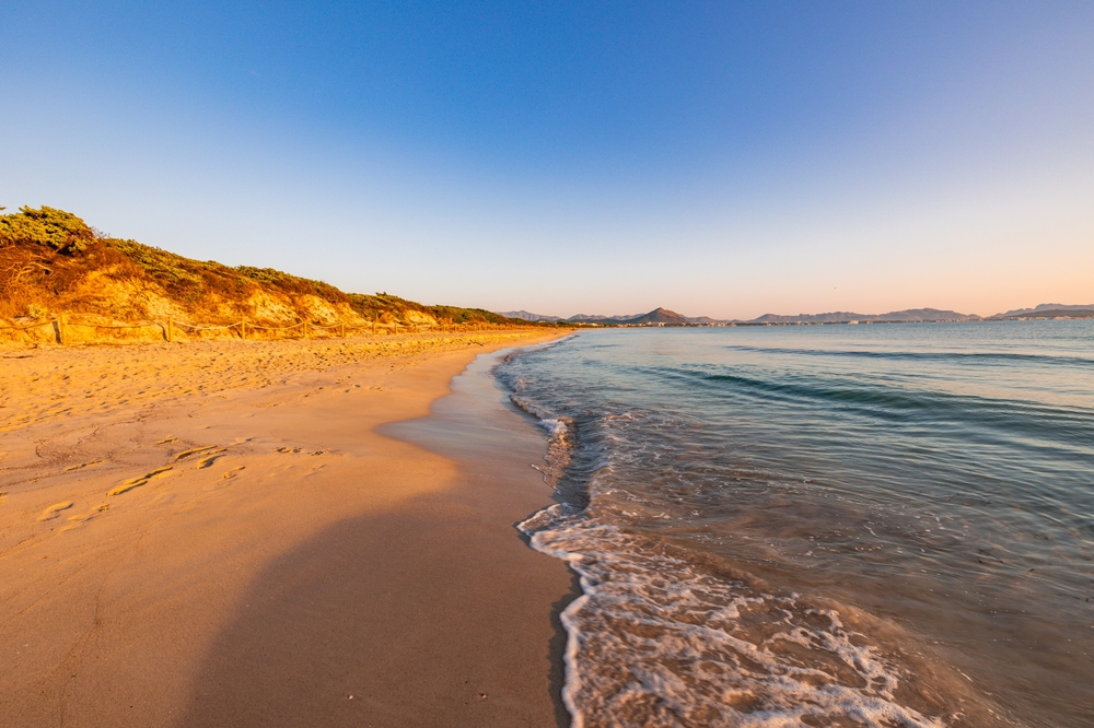 Krásná pláž Playa de Muro na Mallorce s oranžovými odstíny na obloze
