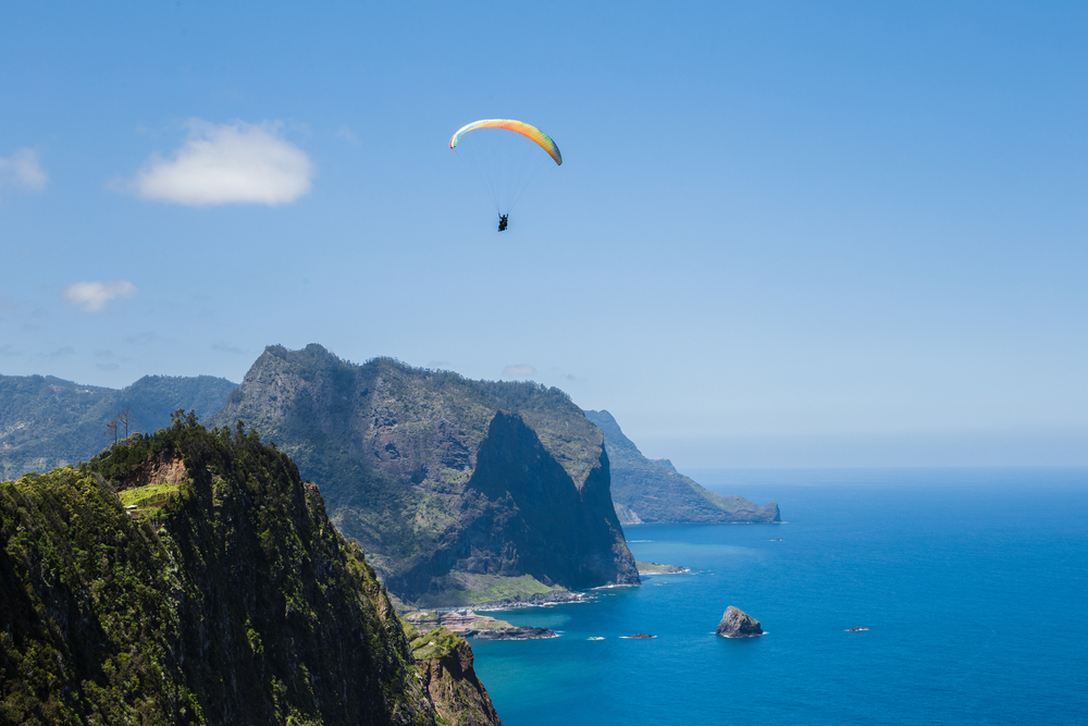 Paragliding nad vesnicí Porto da Cruz s horou Penha D'aguia na pozadí na ostrově Madeira