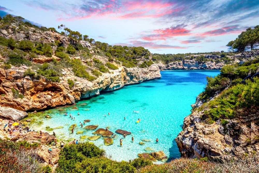 Pláž Caló des Moro na Mallorce obklopená útesy a stromy