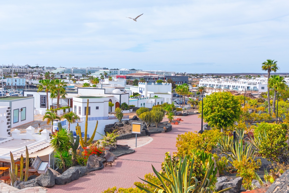 Playa Blanca – co vidět na jihu Lanzarote? 2 Playa Blanca na Lanzarote s bílými budovami, palmami a promenádou pod jasnou oblohou s rackem